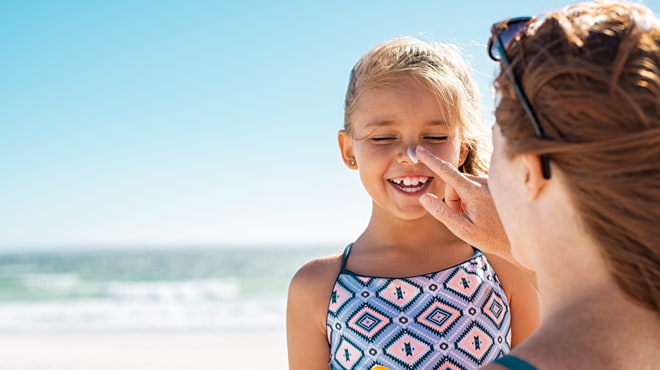 mom putting suncreen on girls nose